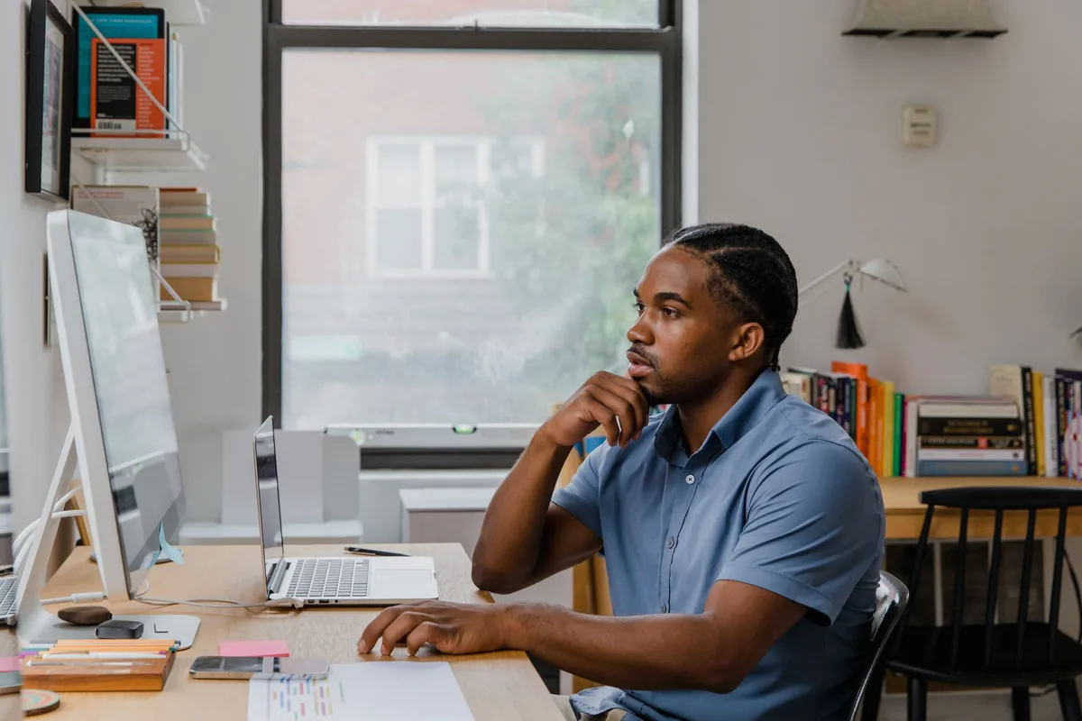 Professional working remotely at a home office desk with natural light, focused on laptop
