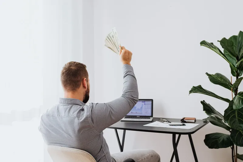 Professional raising cash at home office desk, financial success concept