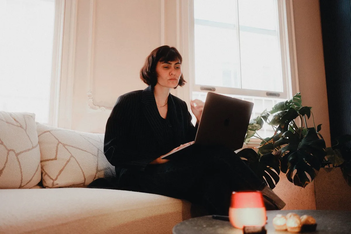 Woman in professional attire working on laptop at home, remote work setup