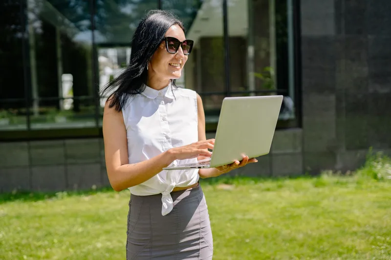 Smiling businesswoman using laptop outdoors, successful remote work