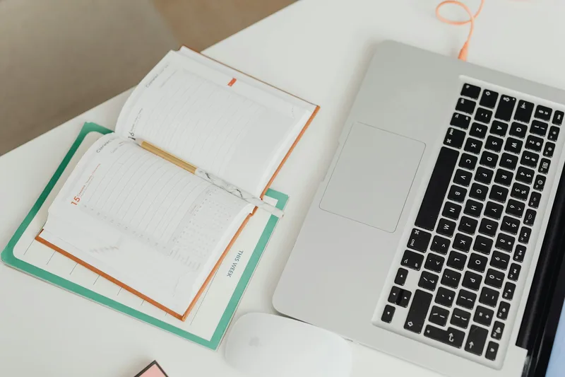 Organized home office workspace with laptop, planner, and earbuds on a clean desk