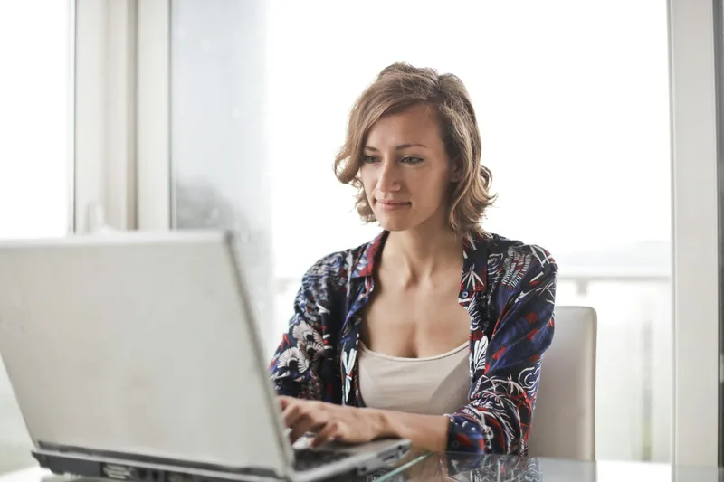 Woman at a laptop in a bright home office setting, reviewing remote job opportunities