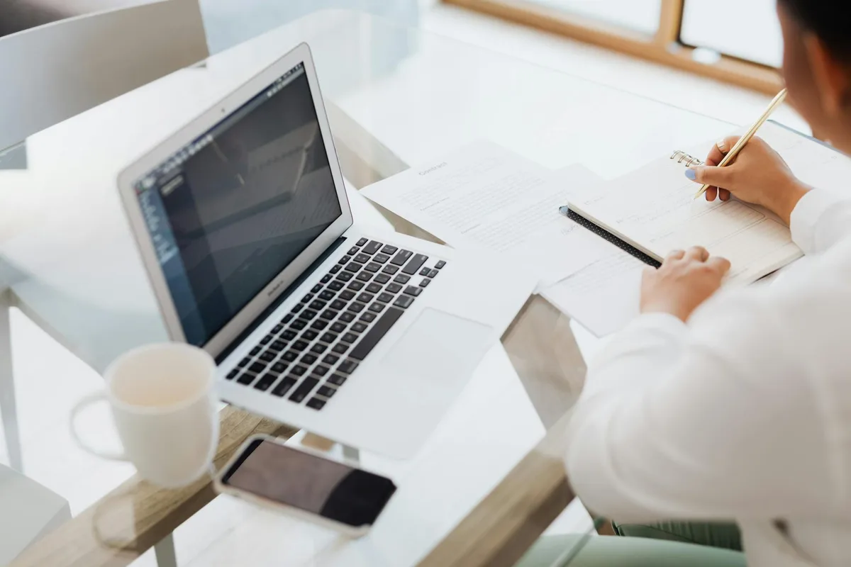 Person working as a remote executive assistant on a laptop at a clean home workspace