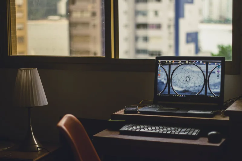 Cozy home office desk with laptop and lamp