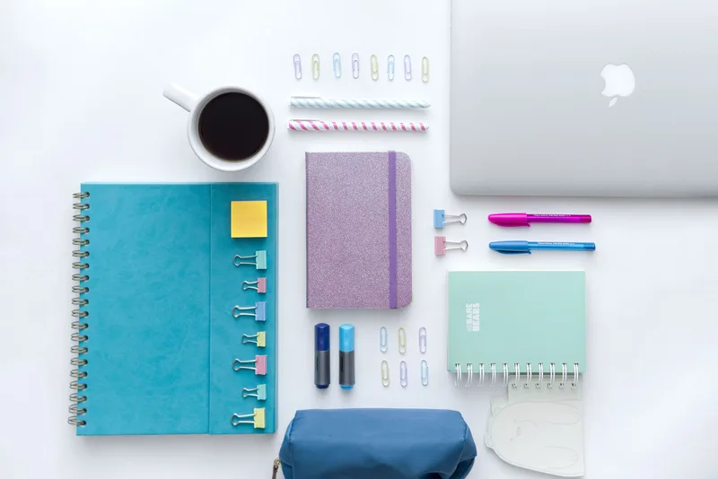 An organized home office desk with a laptop, notebook, and coffee cup