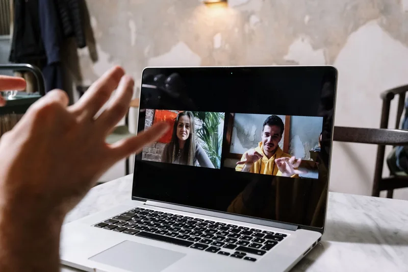 Business team discussing remote work contract terms over a video call on a laptop