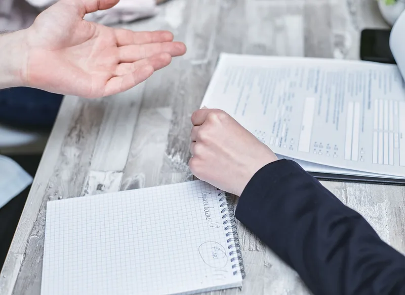Person reviewing paperwork and taking notes at a desk